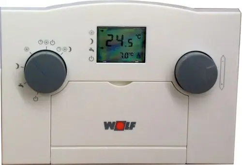 Temperaturregler mit digitalem Display und Drehknöpfen, Marke Wolf, zur Regelung der Heizungstemperatur, montiert an einer Wand.
